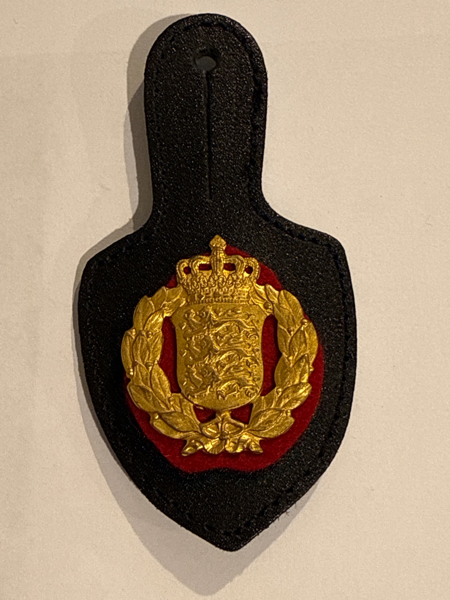Danish Army badge in gilded brass, with leather buttonhole holder.