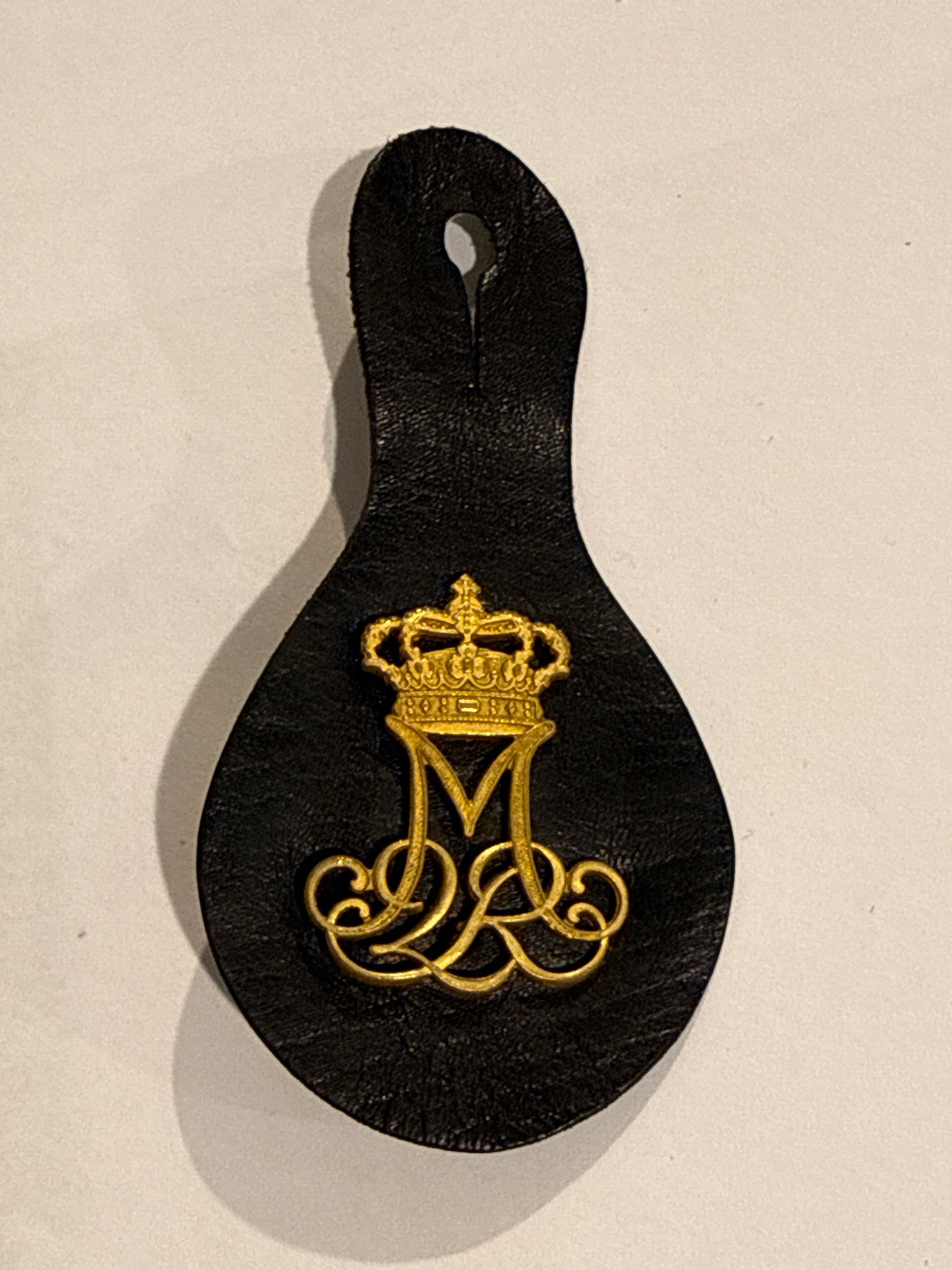 Margrethe d.2. Rex mærke, med knaphulsholder i læder.