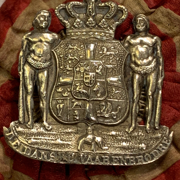 De danske Vaabenbrødre, 1874.  Emblem på roset.