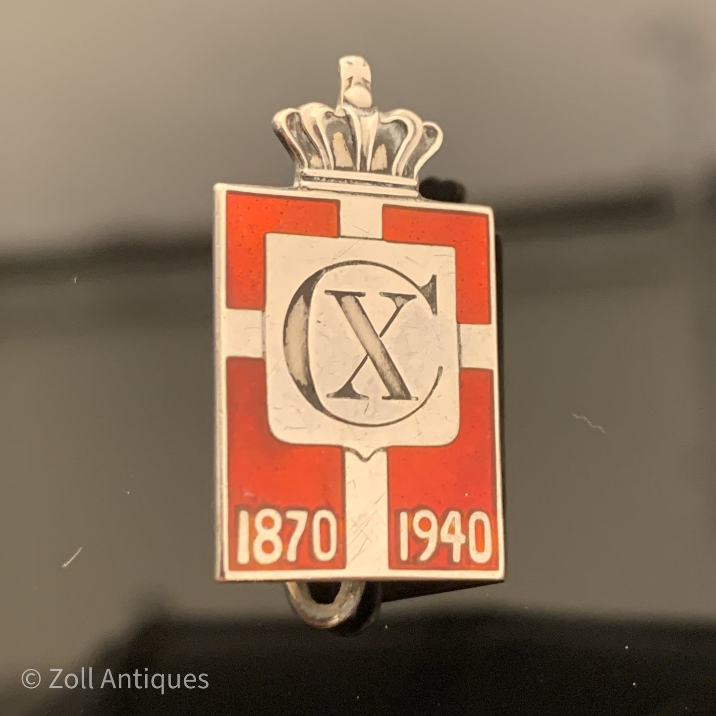Georg Jensen Chr.X. Kongemærke 1870-1940 med nål er et vintage genstand, der er lavet af Georg Jensen. Det er et kongemærke, der v